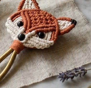 Finished boho fox hair tie macramé pattern with rust forehead, natural cheeks, and black bead eyes on gold elastic loop